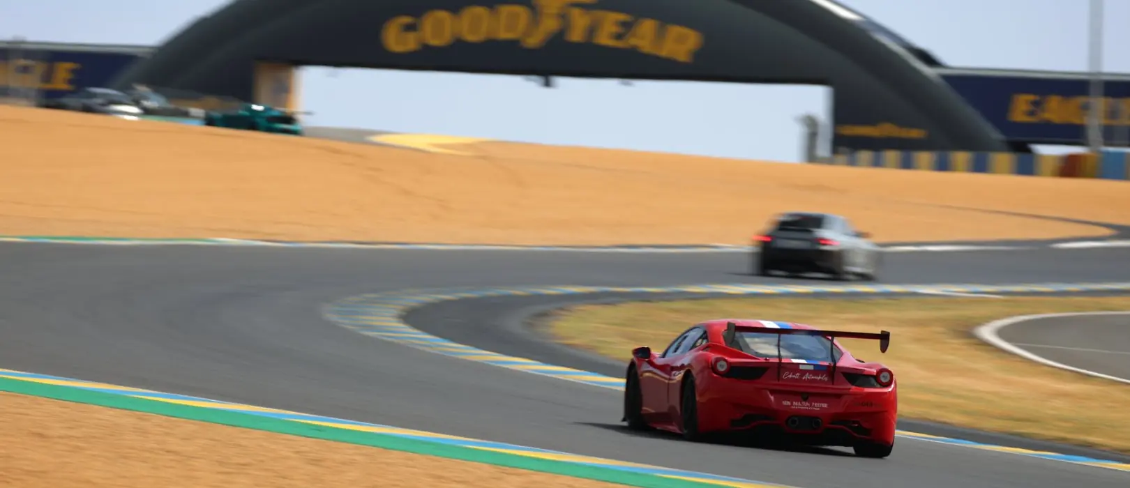 Un coche rojo pasa bajo la pasarela del circuito de Le Mans